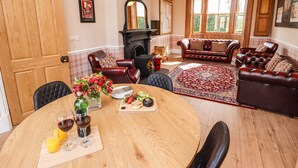 A dining area with a round wooden table, leather chairs, and a red patterned rug.
