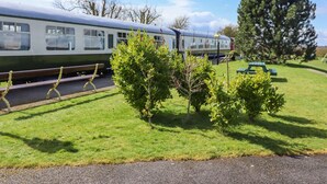 A train on tracks with a picnic table and benches in a grassy area.