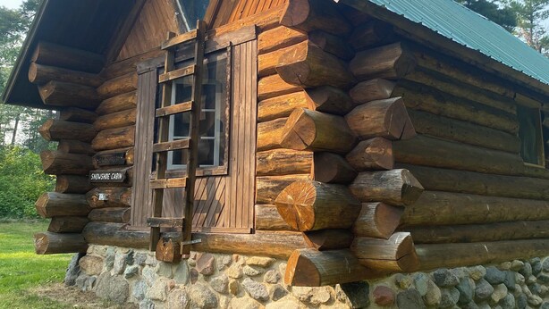 A log cabin with a stone foundation and a metal roof. - Snowshoe Cabin - Spacious Rustic Retreat w/ Loft (Stony River Township)