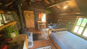 Ein gemütliches Blockhaushaus-Interieur mit einem Bett, einem Esstisch und einer Couch.