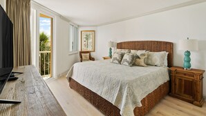 Un dormitorio con una cama grande, televisión y una ventana con cortinas.