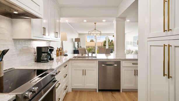 Una cocina moderna con armarios blancos, electrodomésticos de acero inoxidable y una isla central con fregadero y zona de estar.