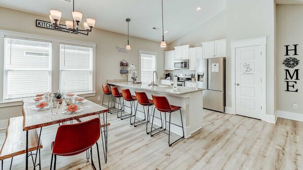 A modern kitchen with white cabinets, a central island, and red bar stools. - New Tucked Away Quiet Beach Haven (Little River)