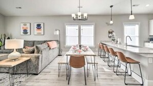 A modern kitchen with a central island, bar stools, and a dining table. - New Tucked Away Quiet Beach Haven (Little River)