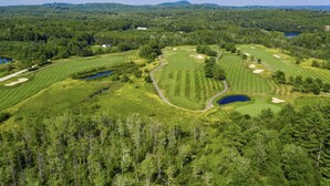 Um campo de golfe com vários buracos, corpos d'água e uma área arborizada.