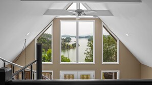 Una habitación con un ventanal que ofrece vistas a un lago y colinas.