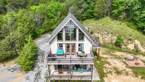 Una casa de dos pisos con balcón, rodeada de un bosque frondoso.