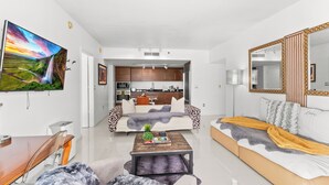 A modern living room with a sofa, coffee table, and a TV mounted on the wall. - 0142 Skyline Serenity 1B/1B (Miami)