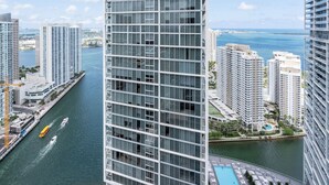 A high-rise building with a modern glass facade, surrounded by other high-rise buildings and a body of water. - 0142 Skyline Serenity 1B/1B (Miami)