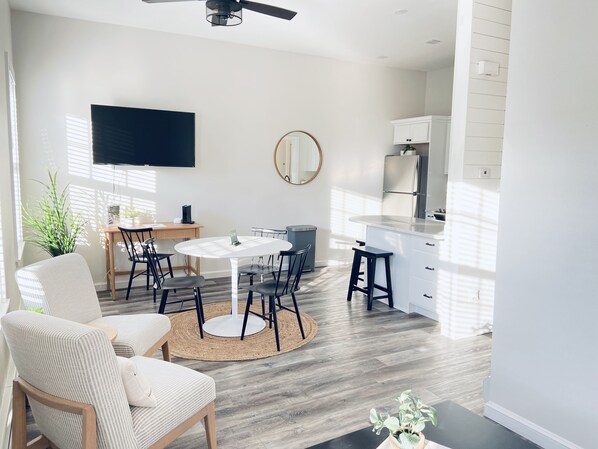 A modern kitchen with a dining area, a flat-screen TV, and a large mirror.