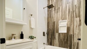 A bathroom with a white vanity, a toilet, a bathtub, and a shower.