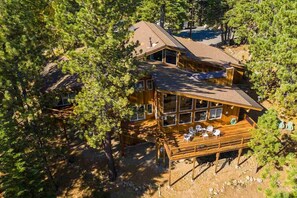 Relax on the spacious deck, surrounded by trees, with a bathtub and outdoor seating.