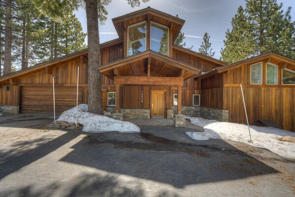 Surrounded by tall pine trees, this cabin features a central tower with large windows and a stone foundation.