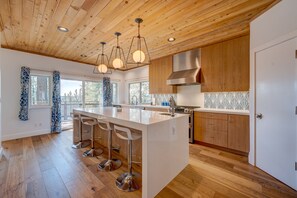 Enjoy cooking in this kitchen with a large island, bar stools, stainless steel appliances, and a view of the surrounding area.