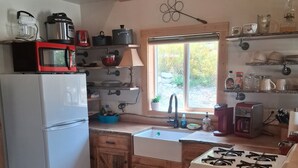 A compact kitchen with wooden cabinets, a white refrigerator, a stove, and various kitchen appliances.