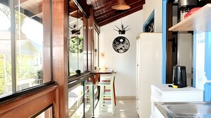 A kitchen with a refrigerator, a sink, and a window overlooking a balcony.