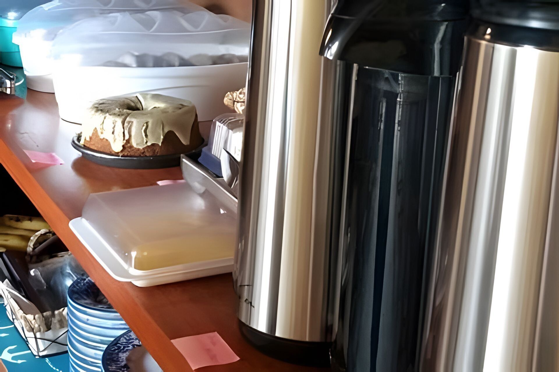 A kitchen counter with a cake on a plate, a coffee maker, and a container of butter.