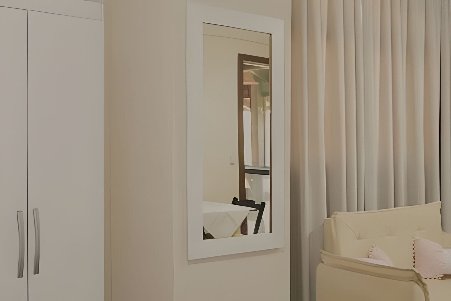 Ein Hotelzimmer mit großem Kleiderschrank, einem Spiegel und einem Sessel mit Kissen.