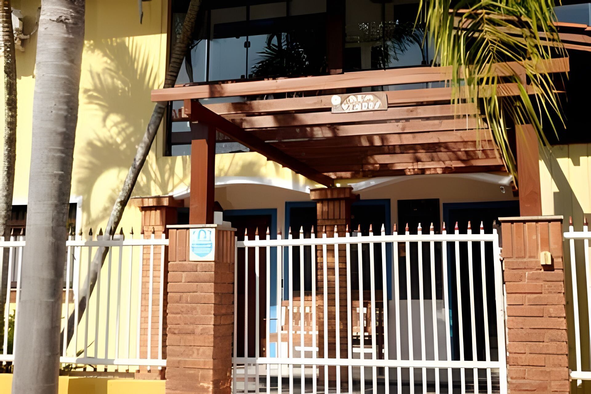 Una entrada protegida por una reja, con un porche de madera y un letrero.