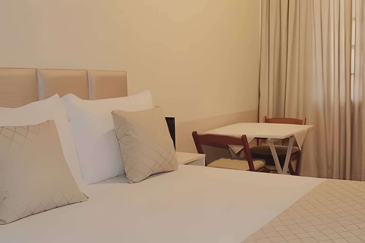 Una habitación de hotel con una cama, una mesita y una silla.