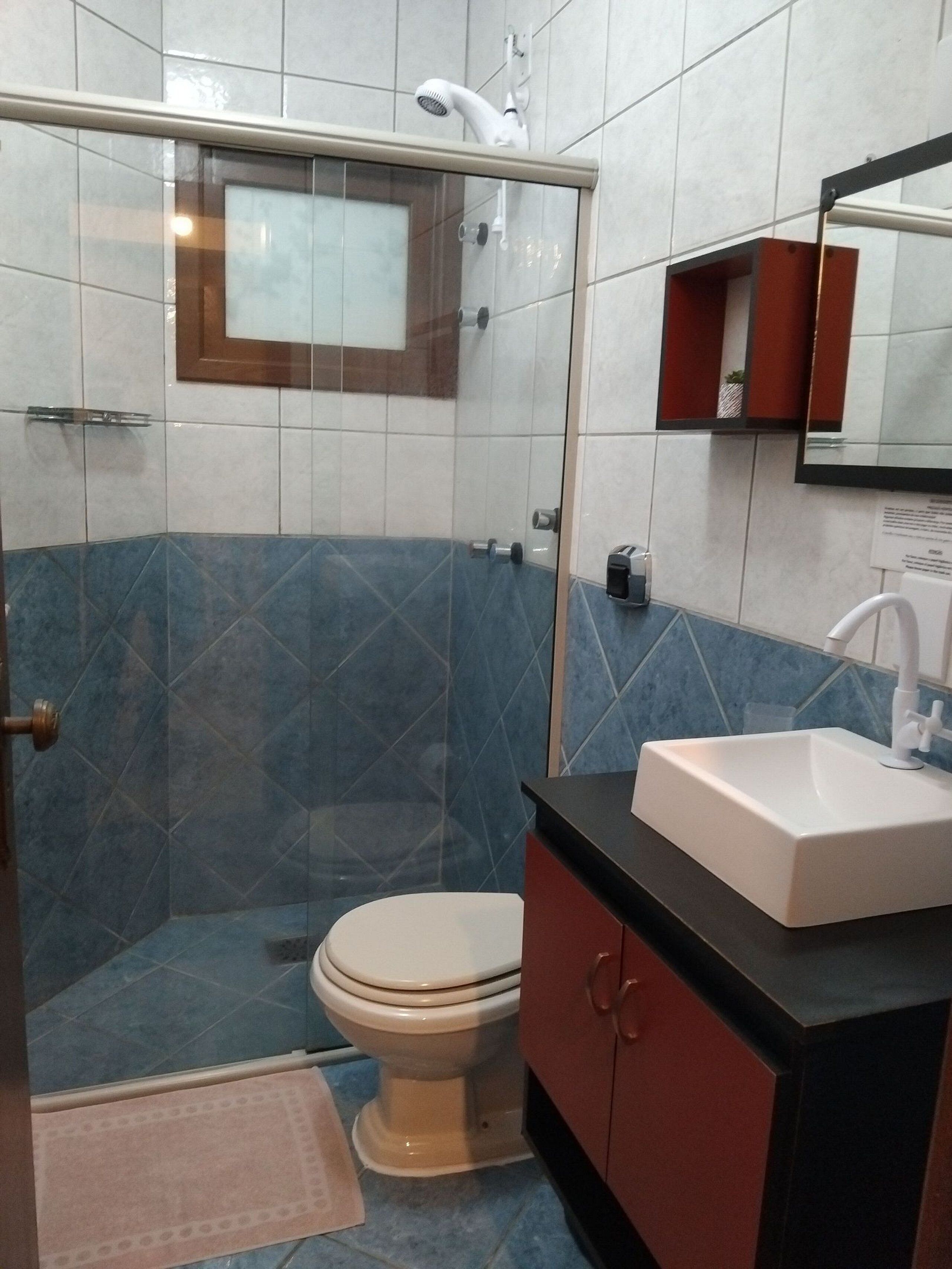 Une salle de bain avec une douche à parois de verre, des toilettes, un lavabo et un miroir.