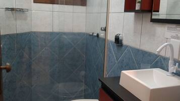 Une salle de bain avec une douche à parois de verre, des toilettes, un lavabo et un miroir.