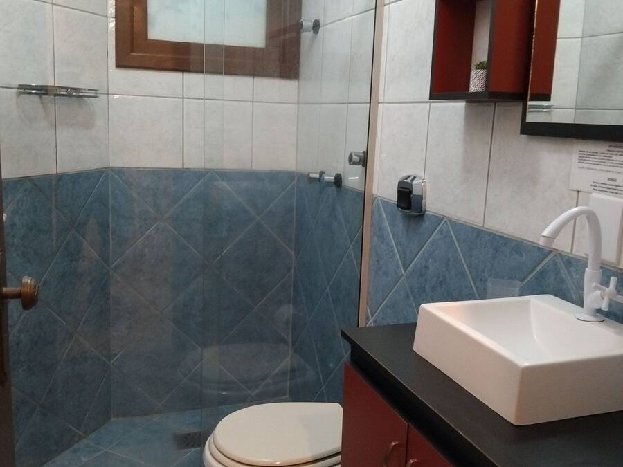 Une salle de bain avec une douche à parois de verre, des toilettes, un lavabo et un miroir.