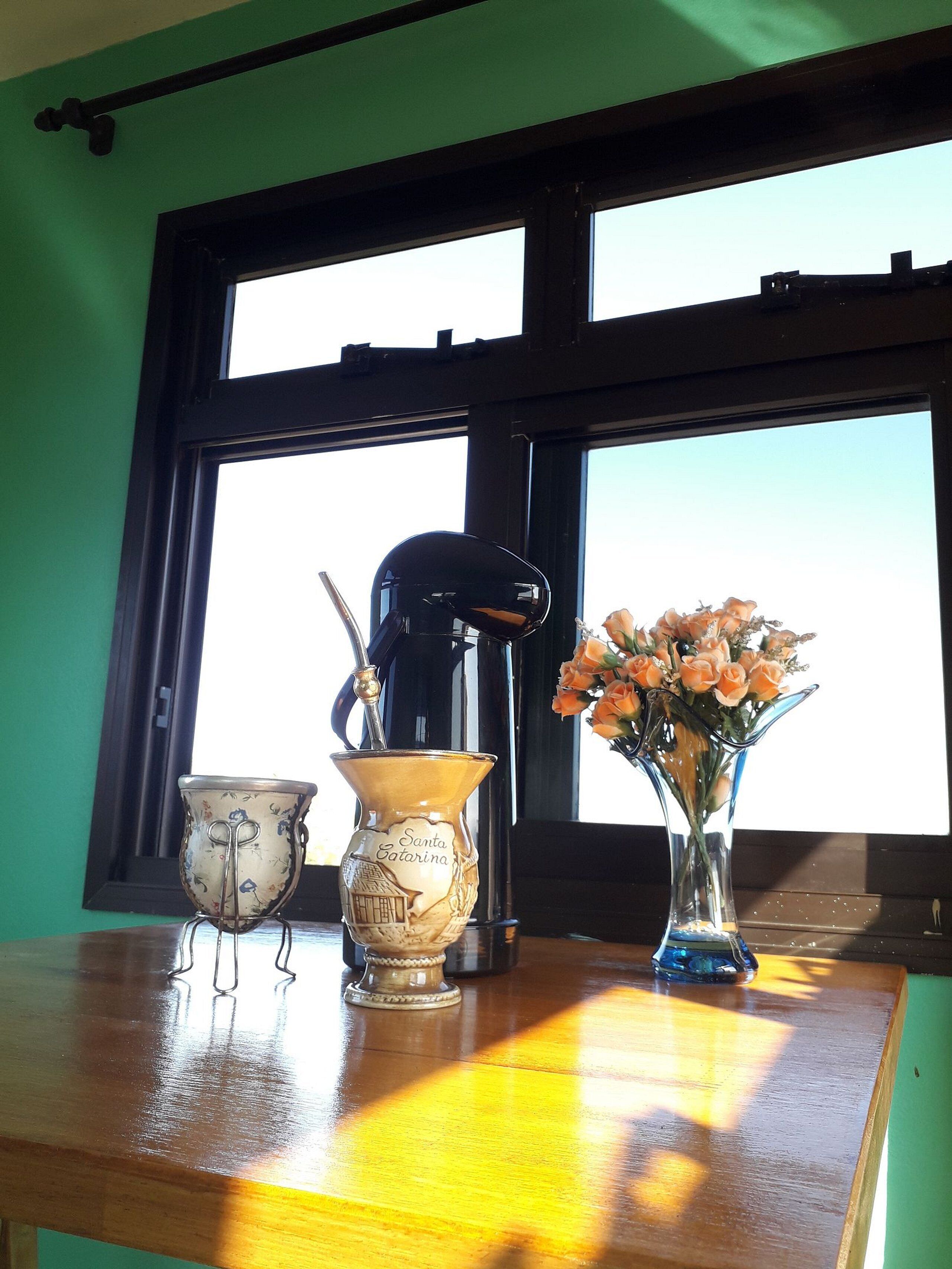 Taula amb una cafetera, una gerra decorativa i un ram de flors.