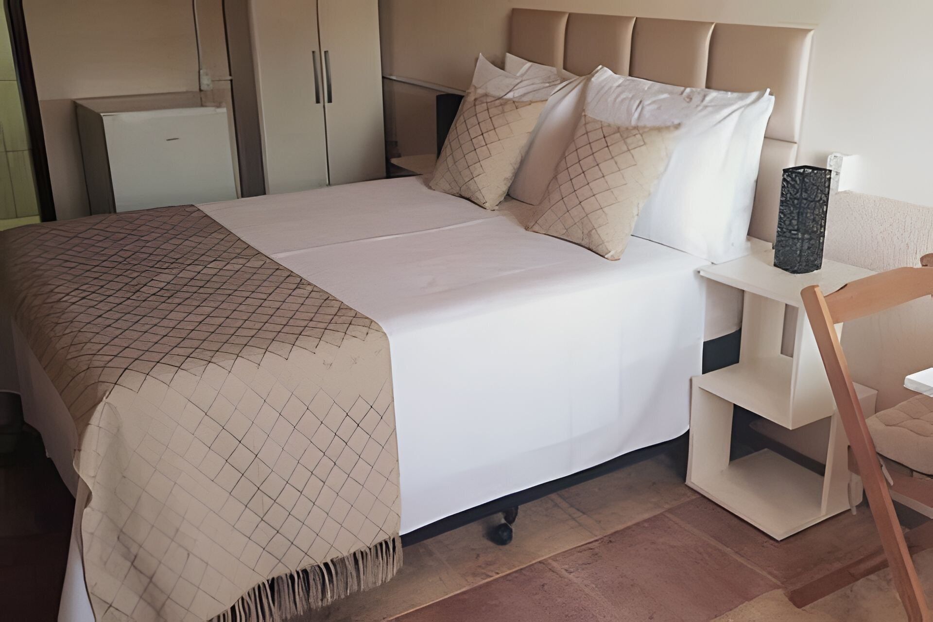 Une chambre à coucher bien rangée, avec un lit, des tables de chevet et une chaise.