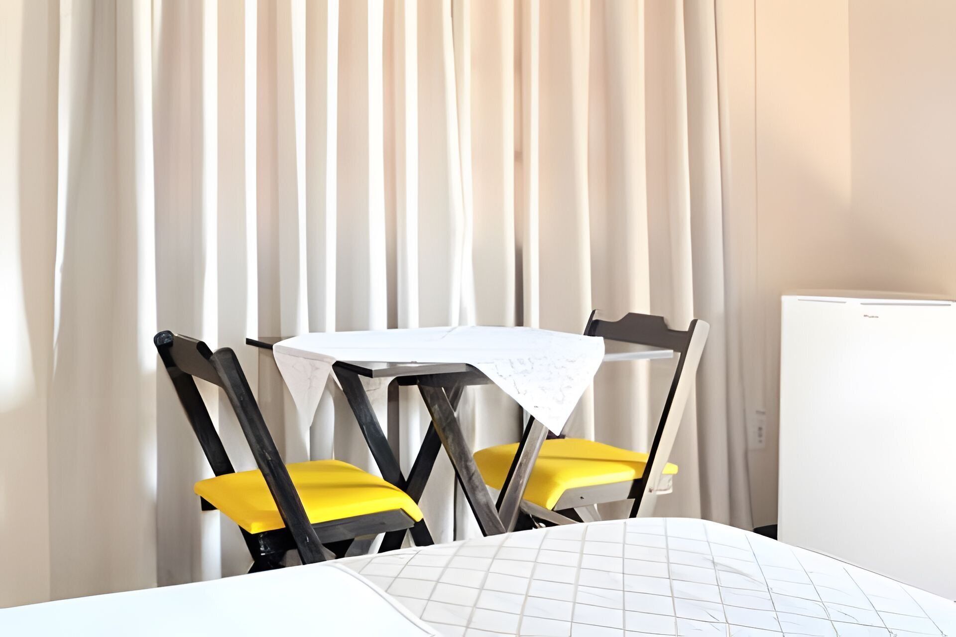 A small room with a round table, two yellow chairs, and a white radiator.