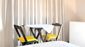 Una habitación pequeña con una mesa redonda, dos sillas amarillas y un radiador blanco.