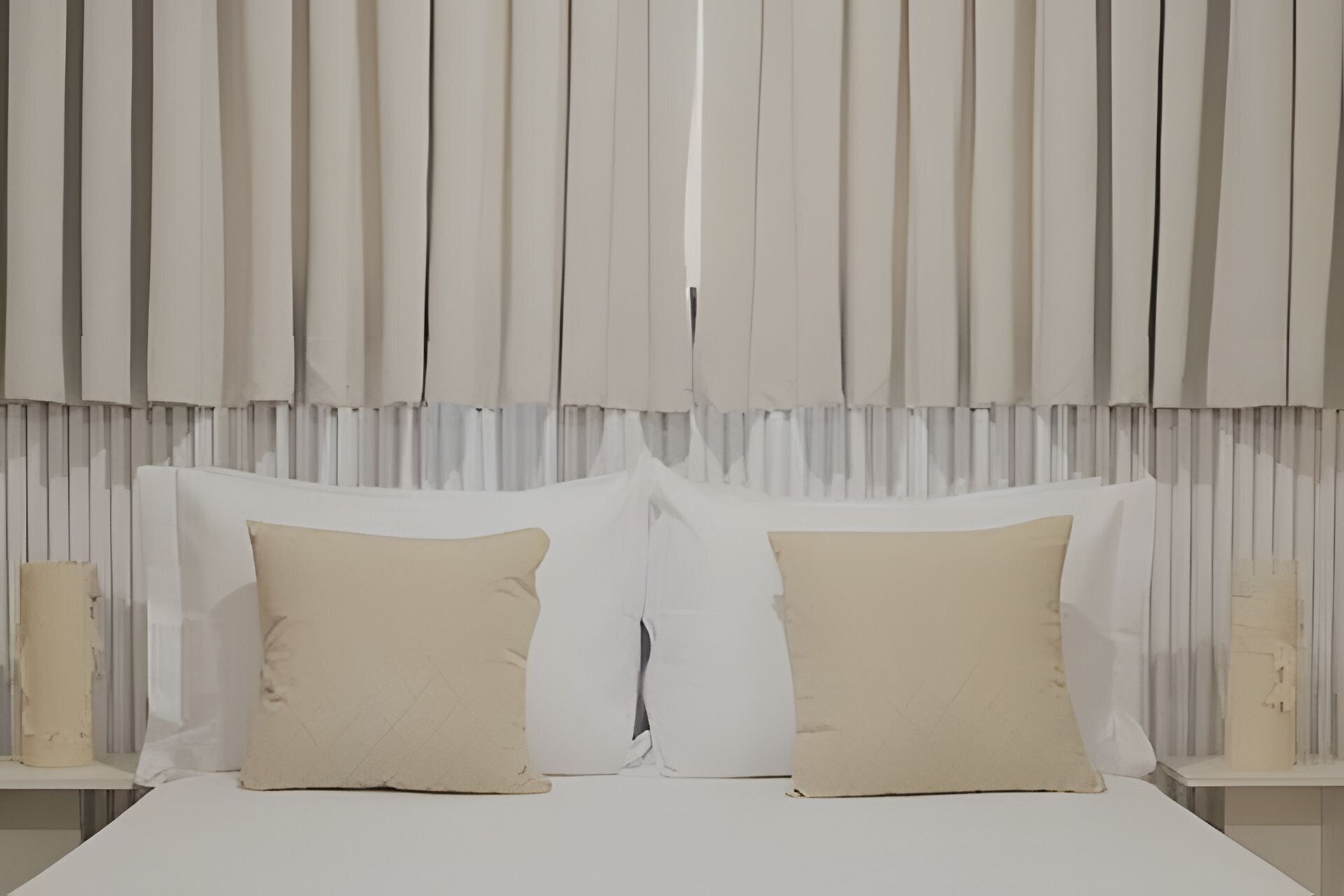 Un dormitorio con una cama grande, dos almohadas y una mesita de noche con una vela.