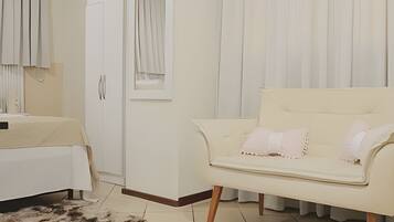 A bedroom with a bed, a white wardrobe, a white sofa, and a fluffy rug.