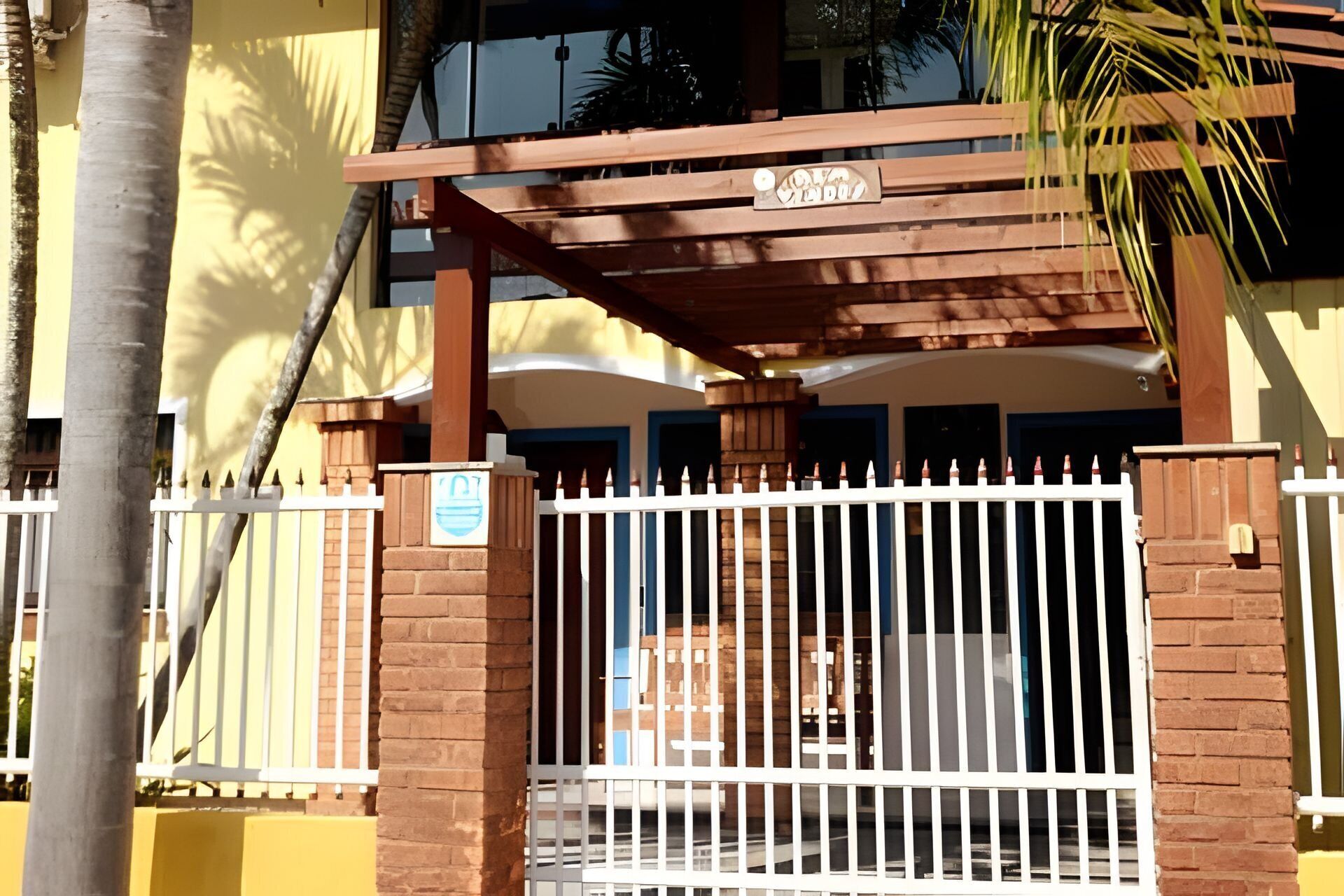 Ein verschlossenes Eingangstor mit einer hölzernen Pergola und einem Schild darüber.