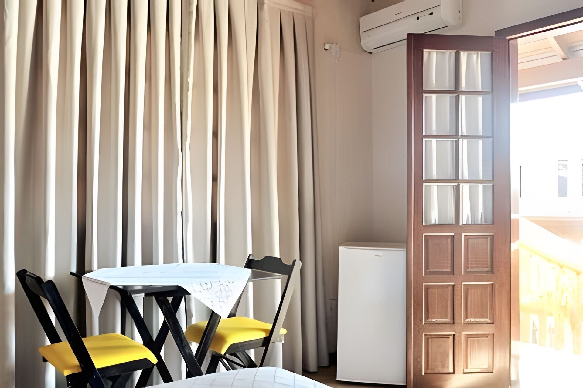 A room with a table, chairs, a white refrigerator, and a door with a window.