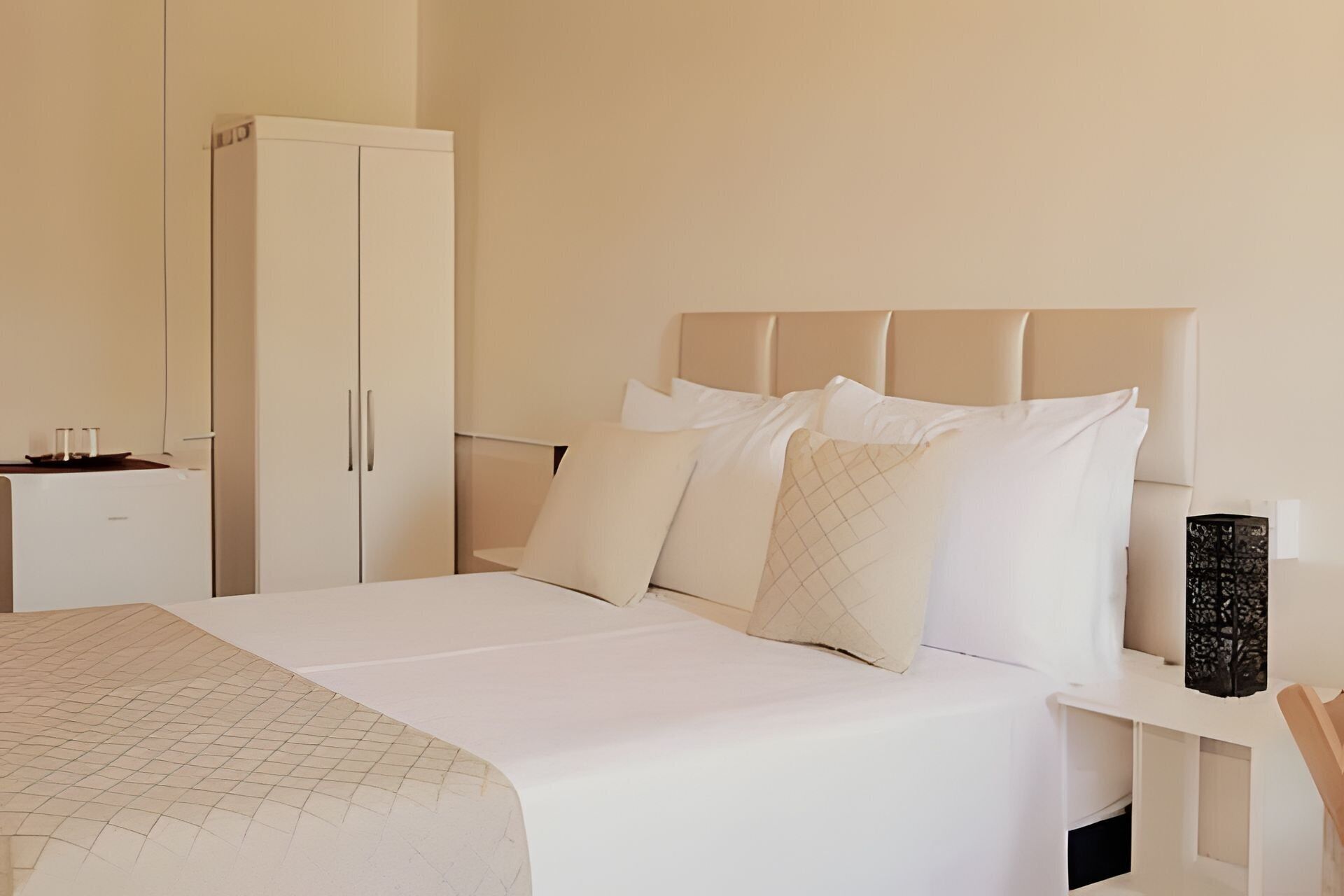 Habitació d'hotel amb llit, armari, taulell de nit i meseta de nit.