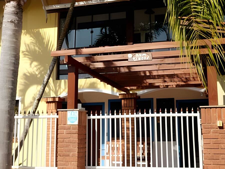 Una entrada protegida por un portón con una pérgola de madera y un cartel encima.