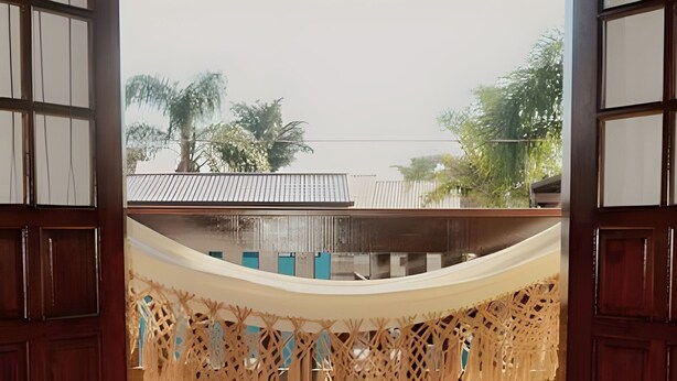 A view through a wooden-framed window with a woven fabric hanging below.