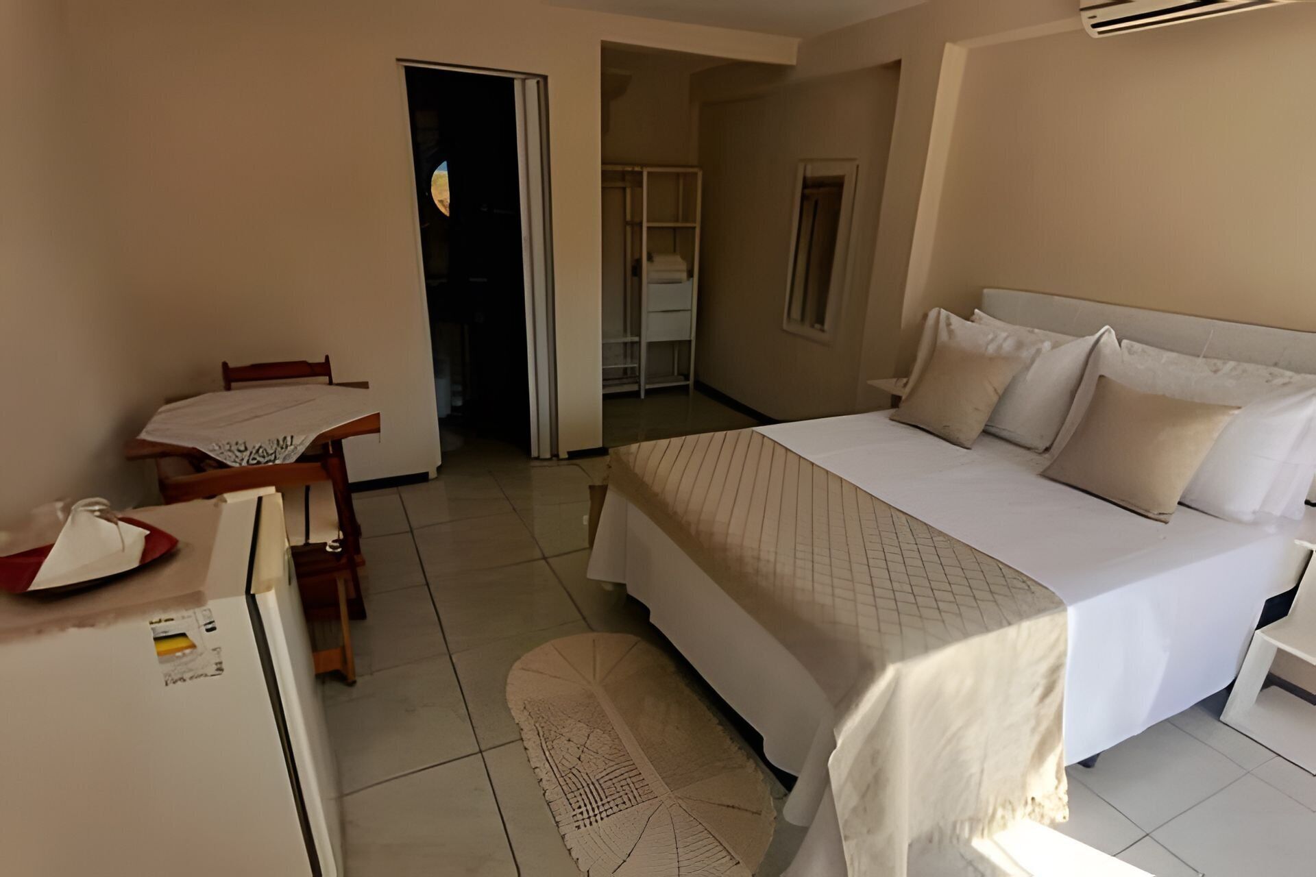 A bedroom with a bed, a desk, and a chair. There is a door leading to another room.