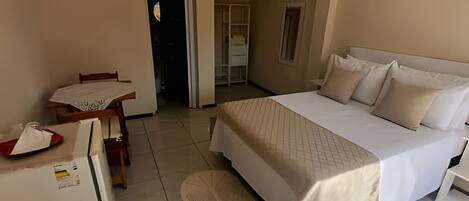 A bedroom with a bed, a desk, and a chair. There is a door leading to another room.
