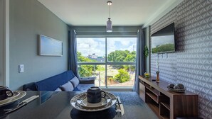 Una habitación moderna con una mesa de comedor, un sofá y un televisor montado en la pared.
