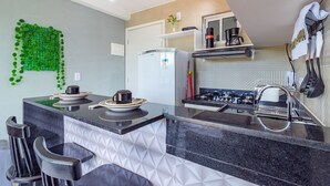Una cocina moderna con una isla central, taburetes de bar, un refrigerador, una estufa y un lavaplatos.