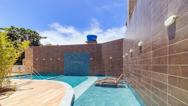 Zona de piscina con pared de azulejos, depósito de agua y sillas de descanso.