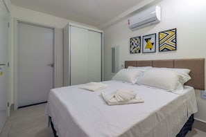 A hotel room with a bed, white linens, a headboard, and three wall art pieces. - Apart Porto de Galinhas por Carpediem (Ipojuca)