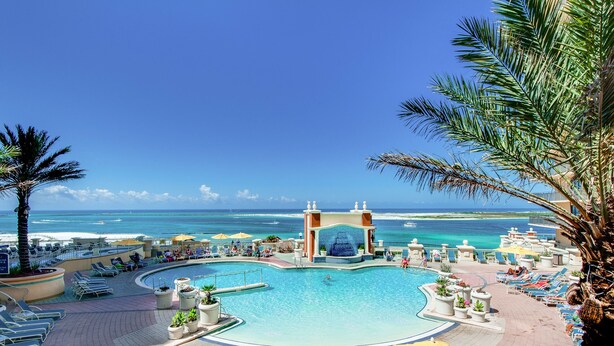 A pool area with a water slide, lounge chairs, and a view of the ocean.