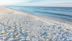 Ein sandiger Strand mit Fußspuren, die zum Wasser führen.