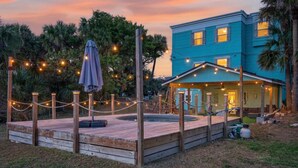 A blue building with a deck, string lights, and an umbrella. - 5 bed 4 bath pool table, fire pit, walk to beach (Daytona Beach)