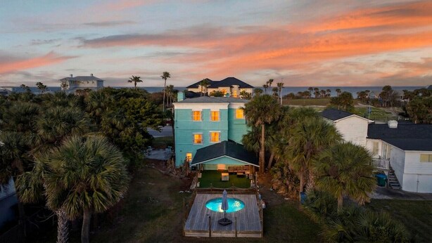 A large house with a pool, surrounded by palm trees and a view of the ocean at sunset. - 5 bed 4 bath pool table, fire pit, walk to beach (Daytona Beach)