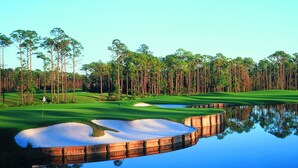 A golf course with sand bunkers, water hazards, and tall trees. - Excellent Management Steps From Beach Pool (Destin)