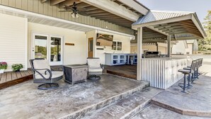 A covered patio with outdoor seating, a bar area, and a 'Welcome' sign on the steps.